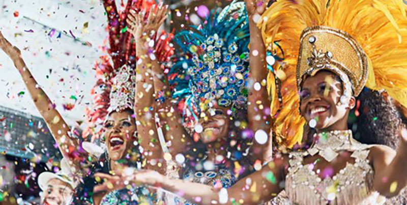 Carnival festivities with three women dressed in vibrant carnival costumes throwing confetti