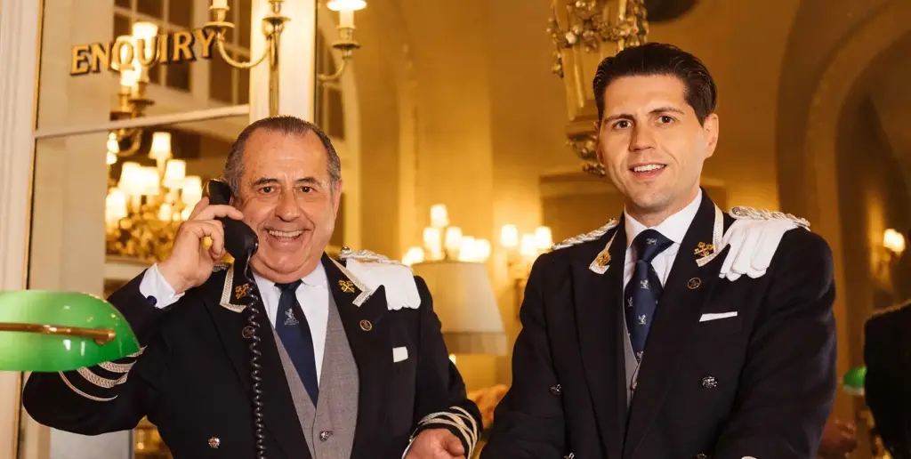 Two members of The Ritz London concierge team behind the reception desk