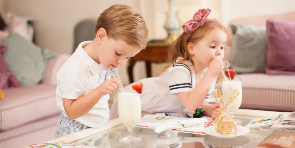 Two children enjoying milkshakes in a hotel suite in The Ritz London