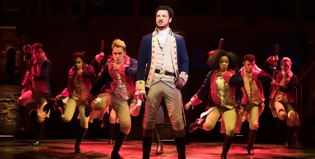 The cast of Hamilton performing on the theatre stage in The West End 