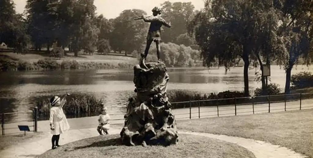 Old fashioned photo of child pointing at Peter Pan statue