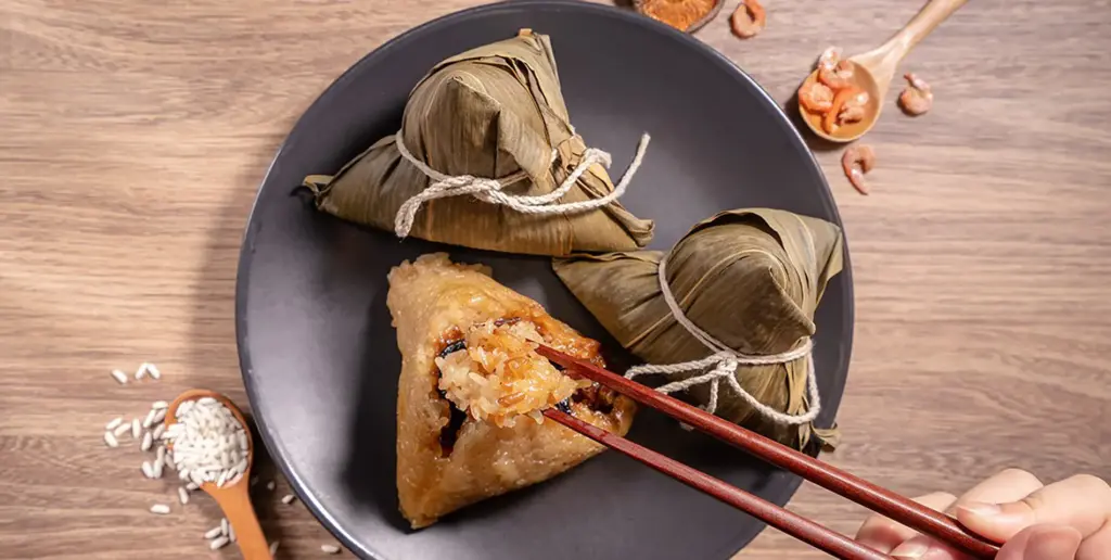 Triangular rice dumpling wrapped in bamboo with chopsticks