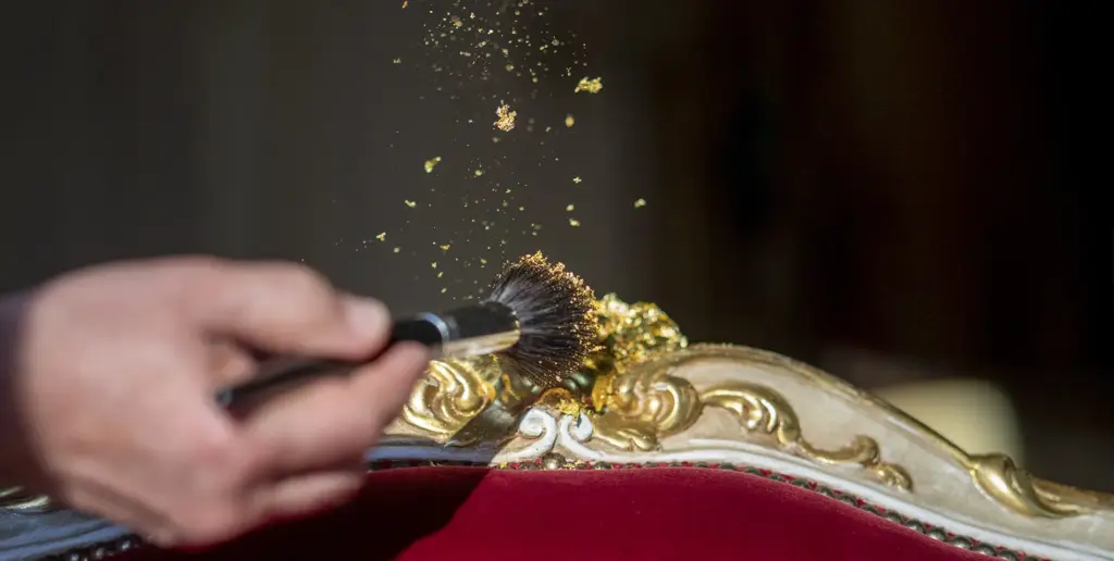 Gold leaf being applied with a brush to a chair